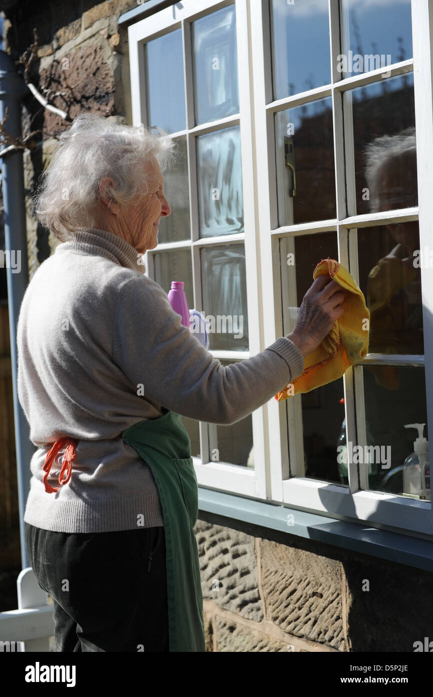 Female pensioner cleaning the windows of her home in North Yorkshire ...