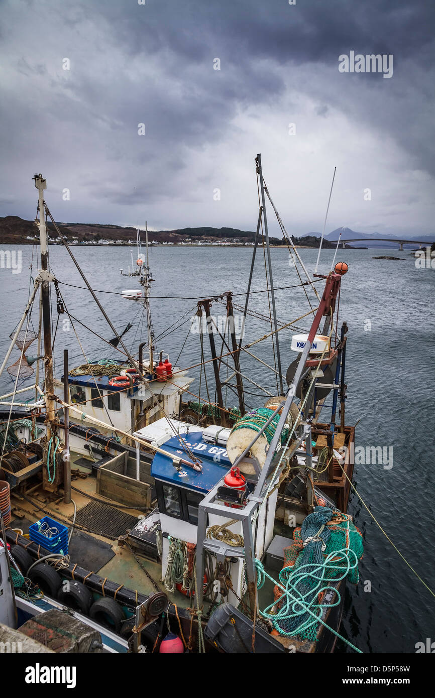 Fishing boats moored in the Kyle of Lochalsh harbour with the Skye Bridge in the distance, West Highlands, Scotland. Stock Photo