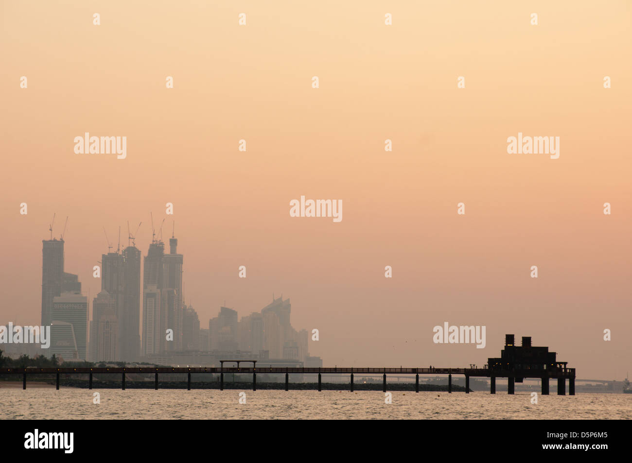 Beautiful sunset in the jumeirah beach of Dunai. In the foreground an offshore restaurant and in the background the marina oif dubai Stock Photo
