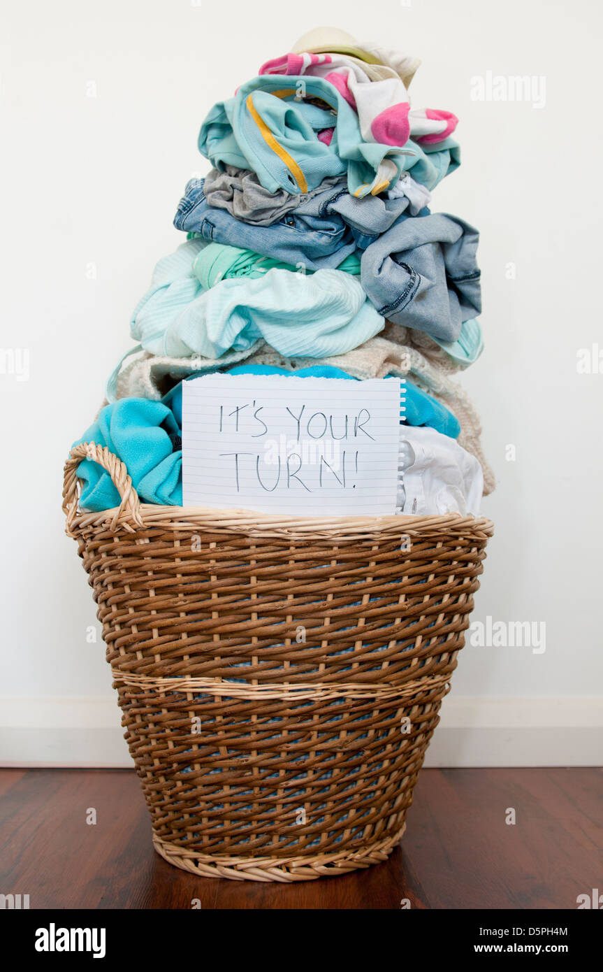 Wicker laundry basket over-filled with laundry Stock Photo