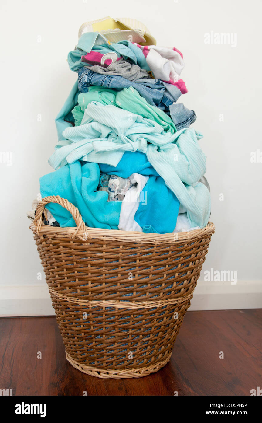 Wicker laundry basket over-filled with washing Stock Photo
