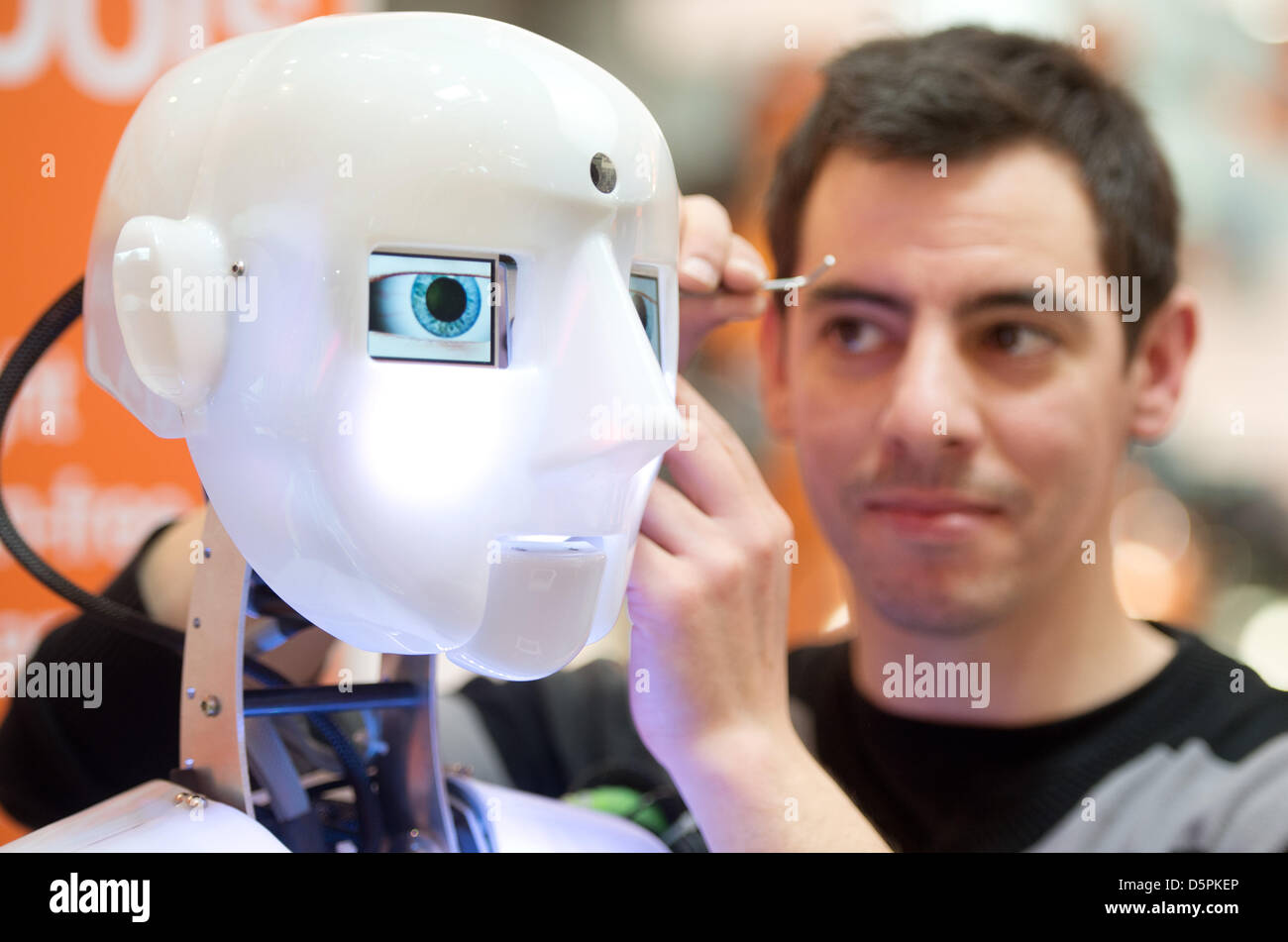 An employee adjusts the costume of a humanoid roboter at the Hanover Fair in Hanover, Germany, 07 April 2013. About 6.500 companies take part in the world's biggest industry exhibition Hanover Fair (Hannover Messe) from 08 to 12 April 2013. Photo: JOCHEN LÜBKE Stock Photo
