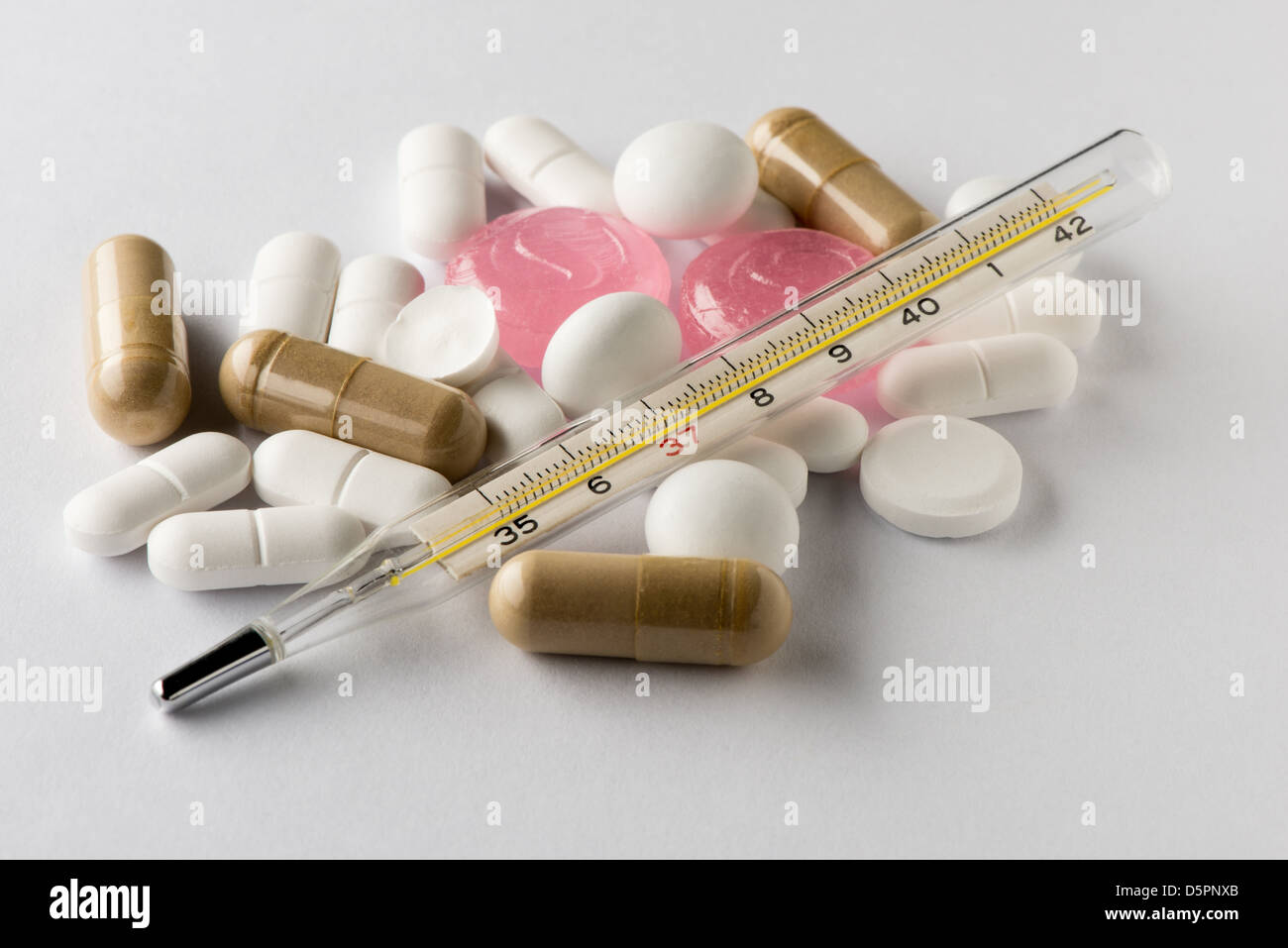 Pile of pills with thermometer Stock Photo