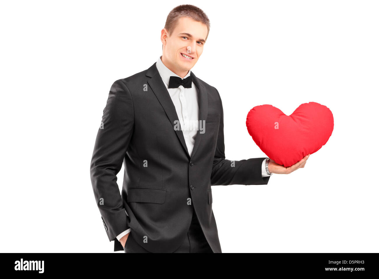 A young man wearing black suit and holding a red heart isolated on ...