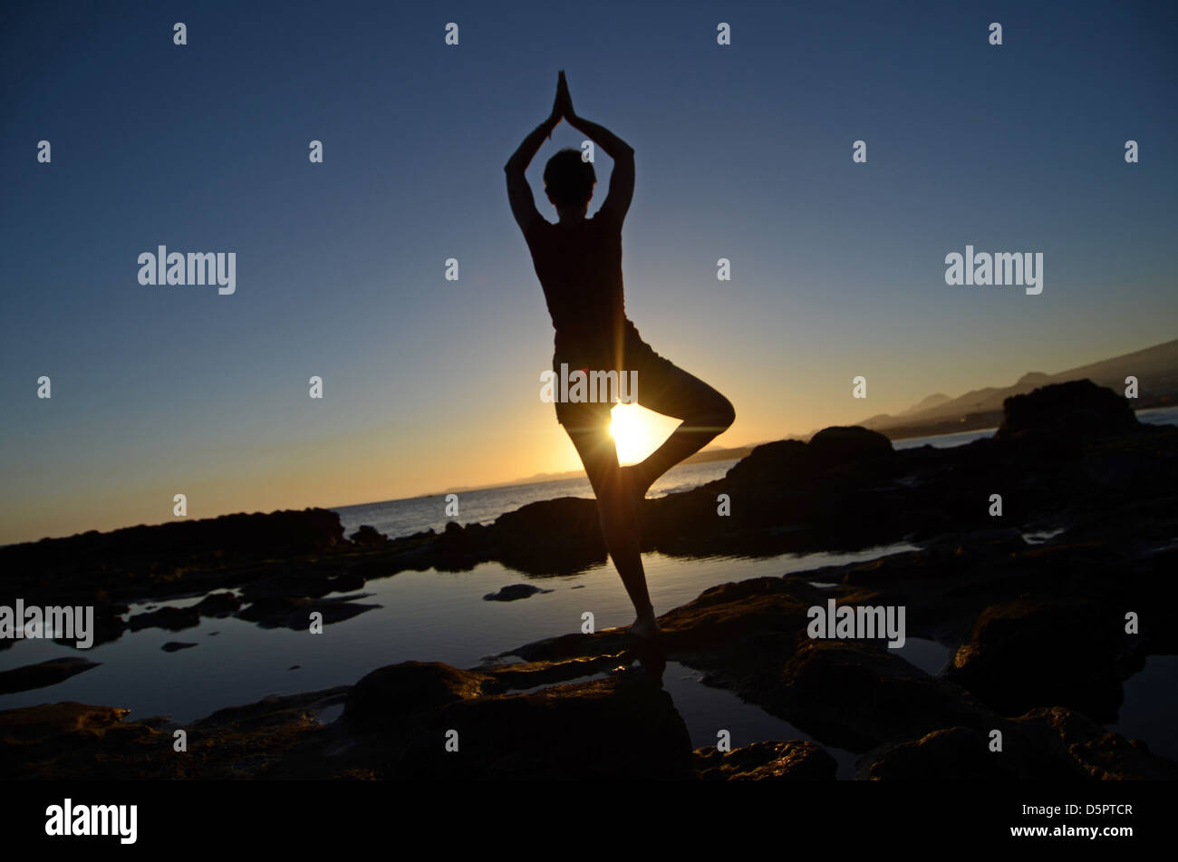 Young woman in tree pose, on the coast Stock Photo