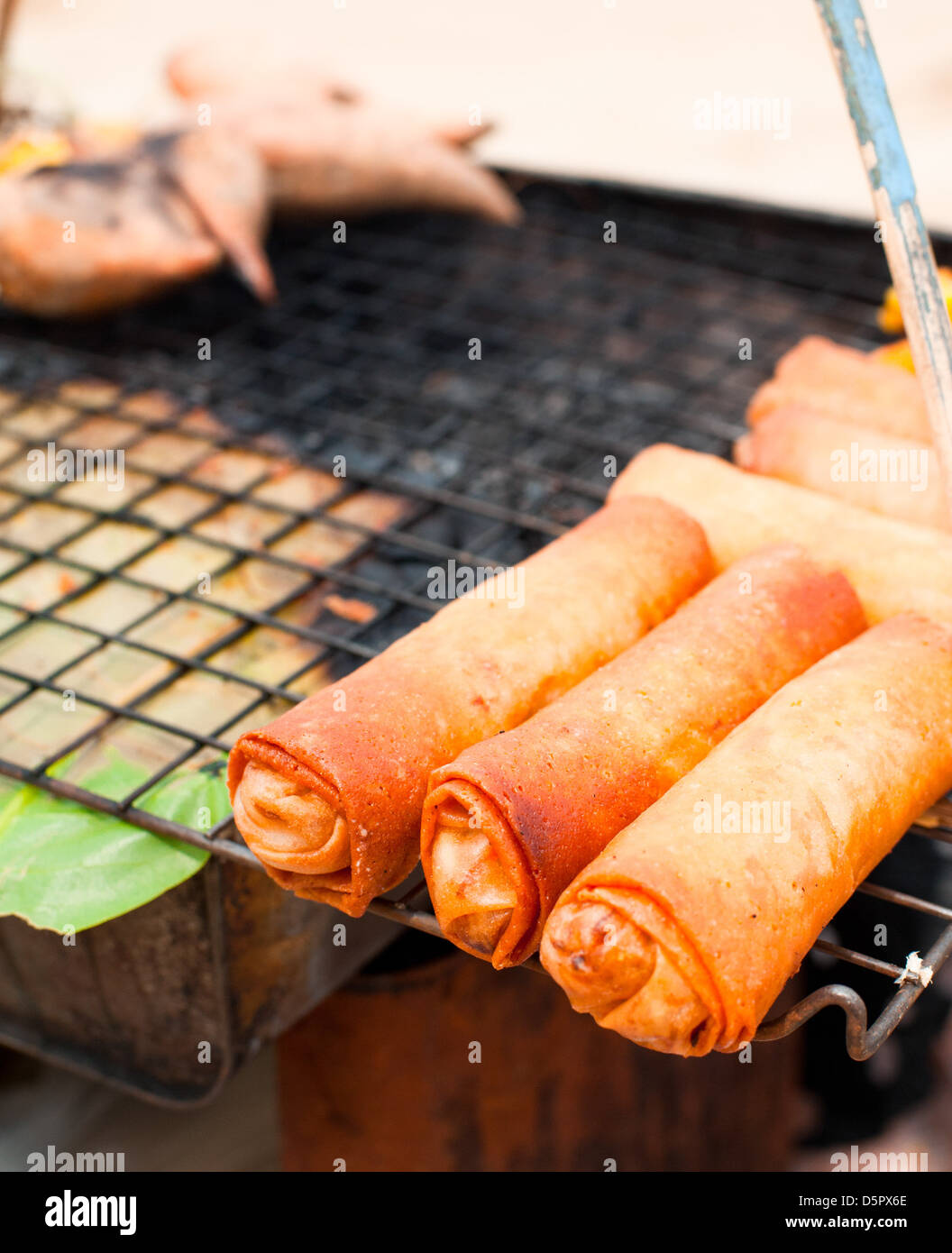 Traditional Thai food at market. Spring rolls on grill Stock Photo