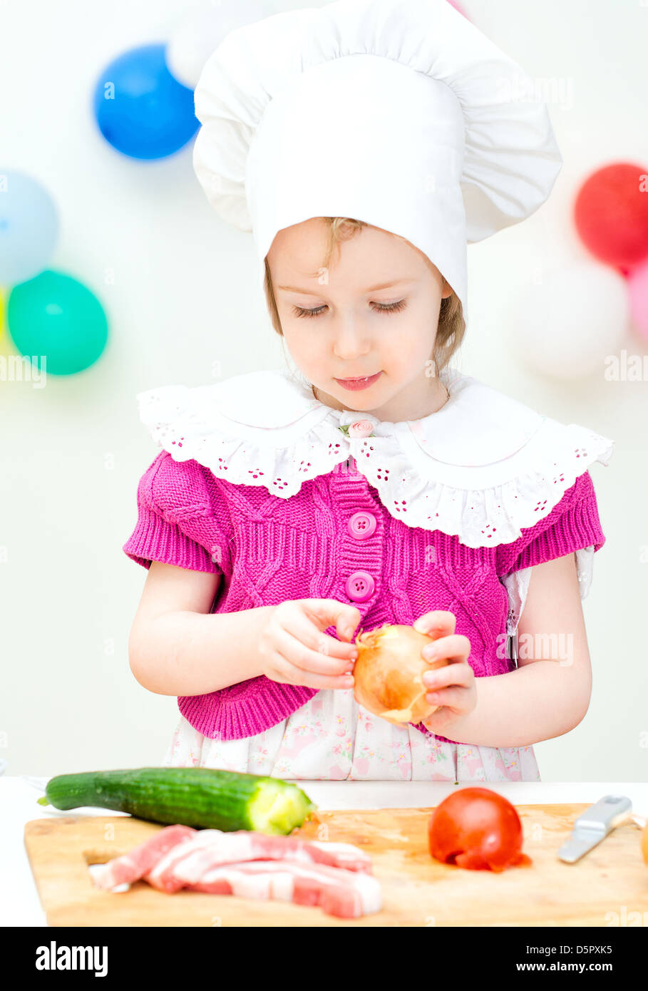 Little girl in chief hat cooking dinner Stock Photo