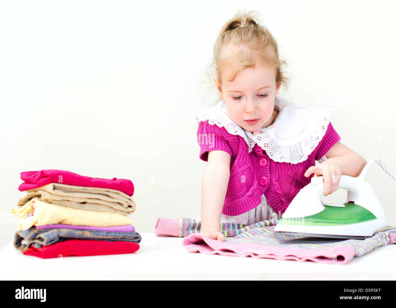 Cute little girl ironing clothes Stock Photo
