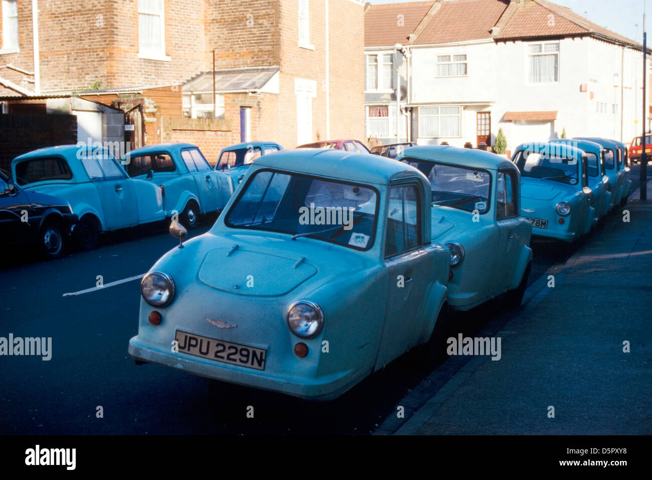unusual sight of a line up of three wheeled ac thundersley invalid cars in an urban street near