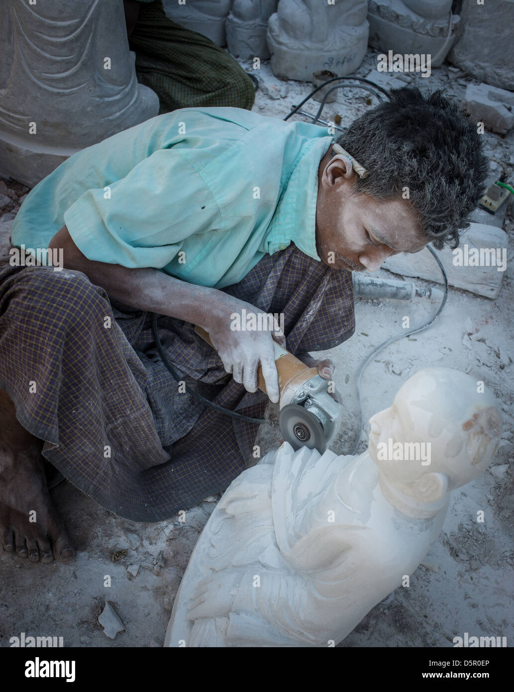 Man carving Buddha statue from white marble Stock Photo