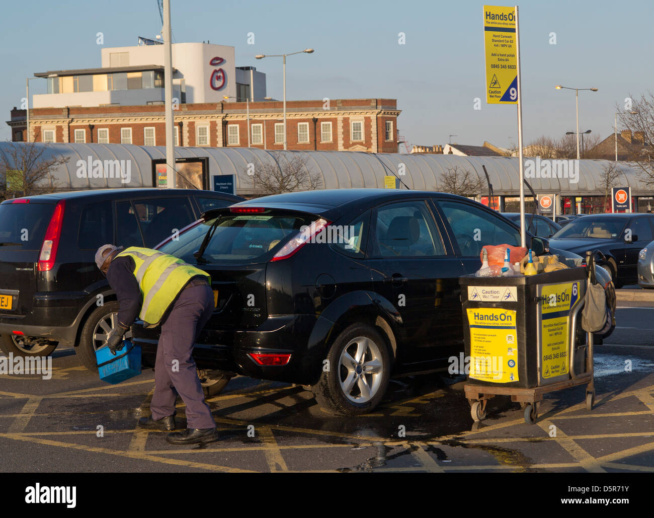 Man working in a car valet cleaning service in a supermarket car park