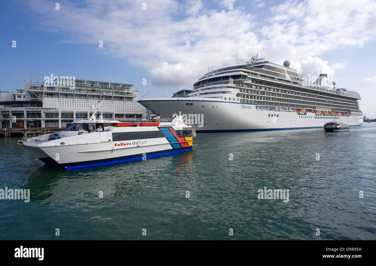 Ferries arriving at the Auckland Ferry Terminal pass the cruise Liner Marina moored in the harbour. Stock Photo