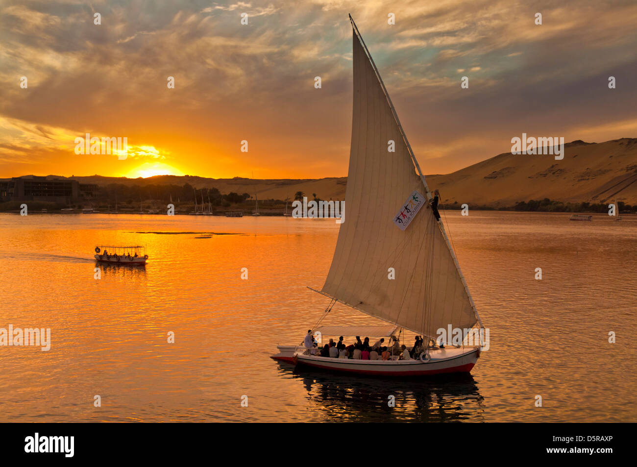 Traditional wooden sailing boats or Feluccas at sunset sailing on the river Nile at Aswan Egypt Middle East Stock Photo