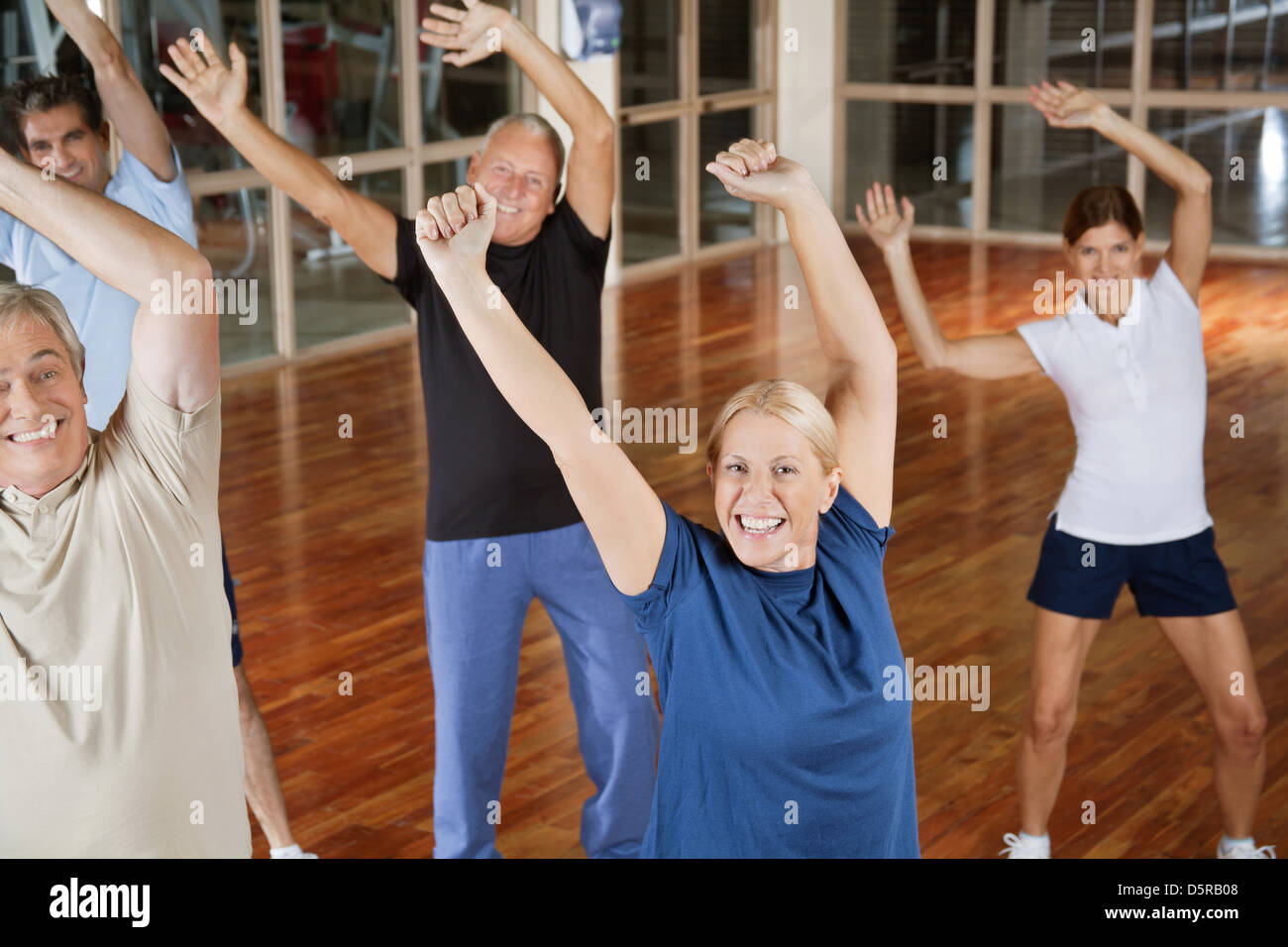 Happy male and female seniors dancing to music in gym Stock Photo