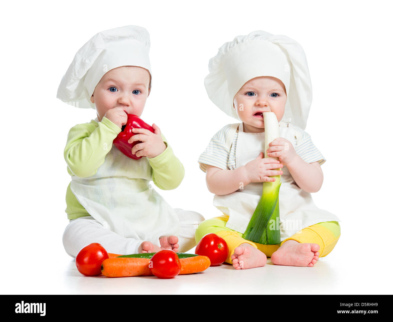 babies boy and girl wearing a chef hat with healthy food vegetables Stock Photo