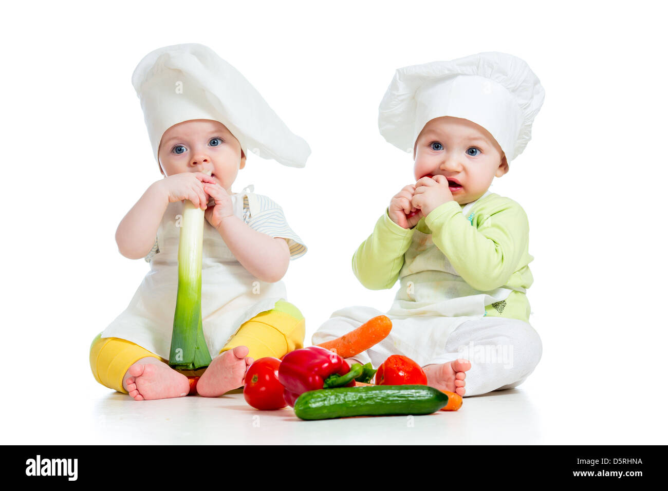 babies boy and girl wearing a chef hat with healthy food vegetables Stock Photo