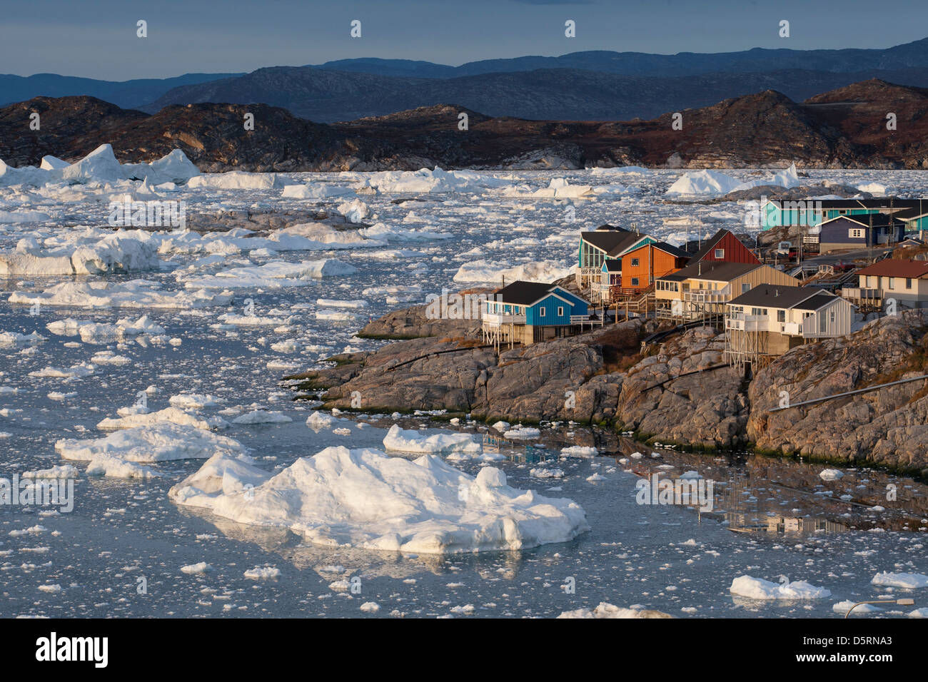 Colourful wooden houses by sea with iceberg fragments, Ilulissat (Jakobshavn), Greenland Stock Photo