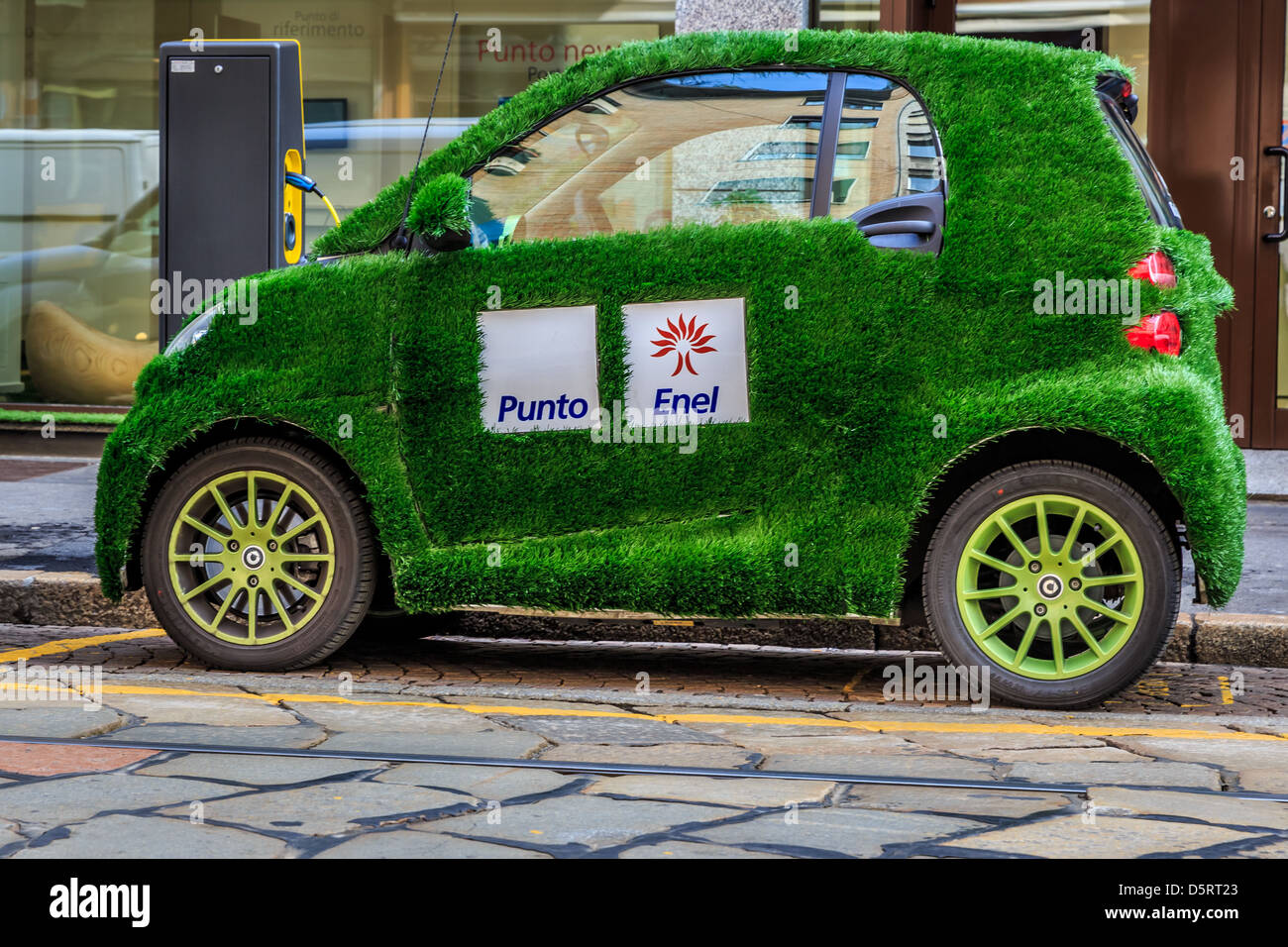 An electric Smart car with grass cover and Punto Enel markings, Milan, Italy Stock Photo