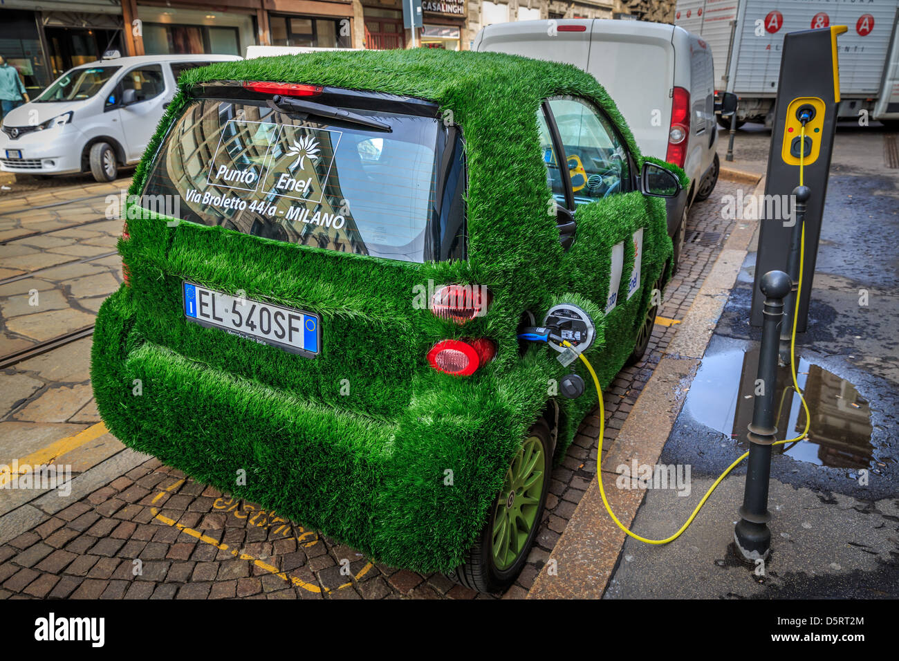 An electric Smart car  with grass cover and  Punto Enel markings, Milan, Italy Stock Photo