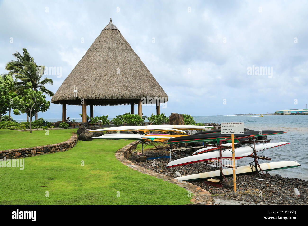 Kayak storage racks and thatched roof gazebo along the shoreline at Paofai Gardens, Papeete, Tahiti. Stock Photo