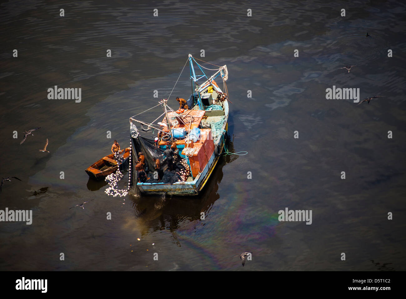 Small fishing boat at the polluted waters of Guanabara Bay, Rio de Janeiro, Brazil. Oil spill near Paqueta island. Stock Photo