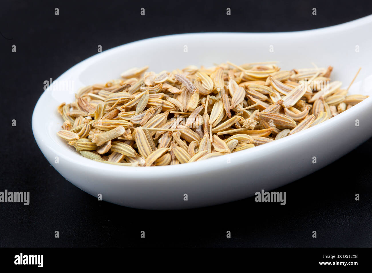 Fennel seeds in the spoon on black background Stock Photo