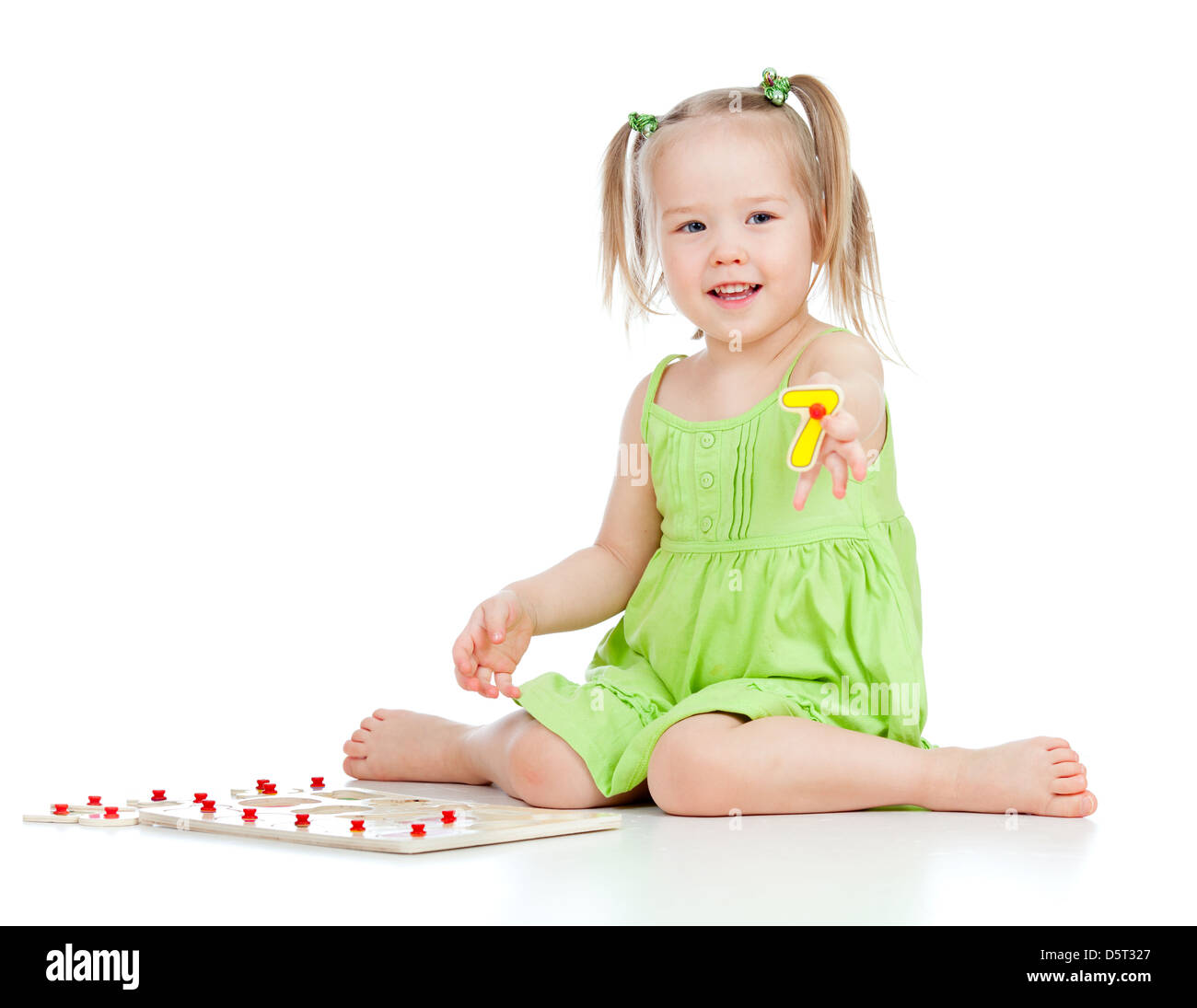 little girl in green dress playing puzzle game on floor on white ...