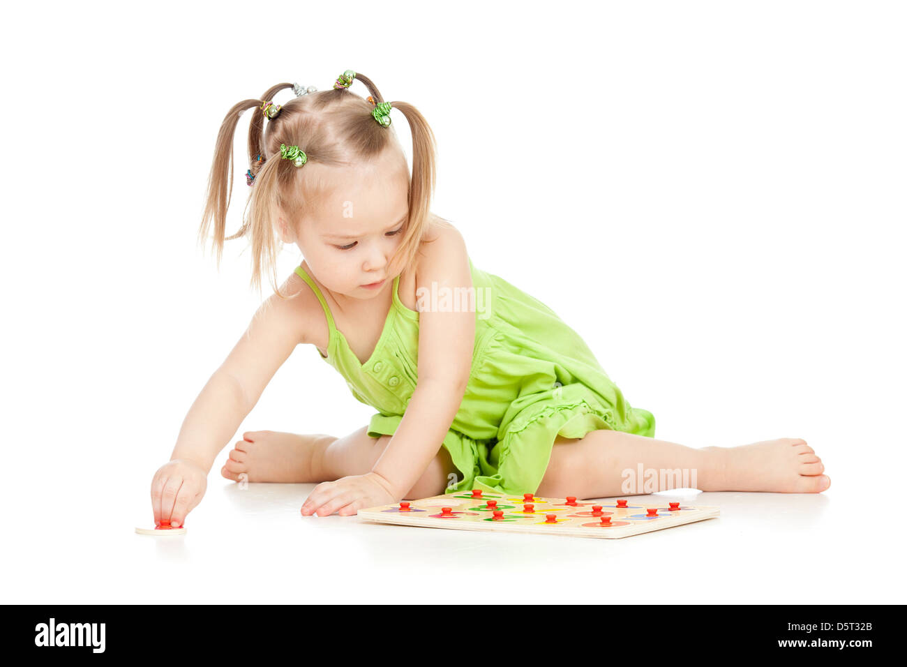 little girl in green dress playing puzzle game on floor on white ...