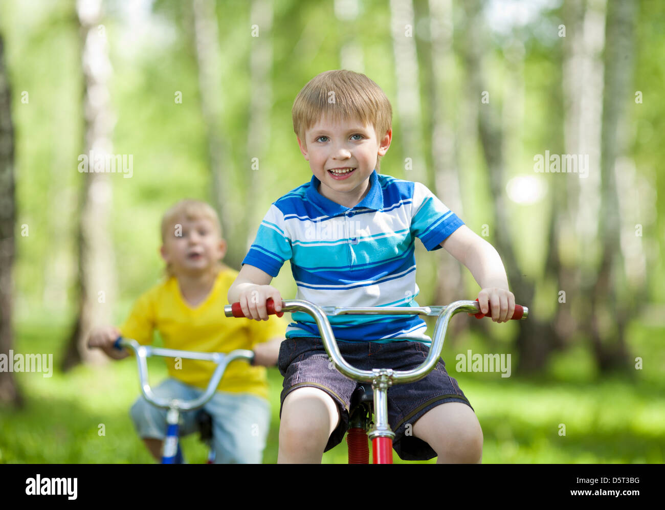 little kids riding their bikes in park Stock Photo