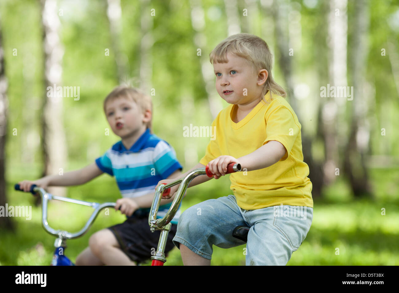 cute kids riding their bikes in park Stock Photo