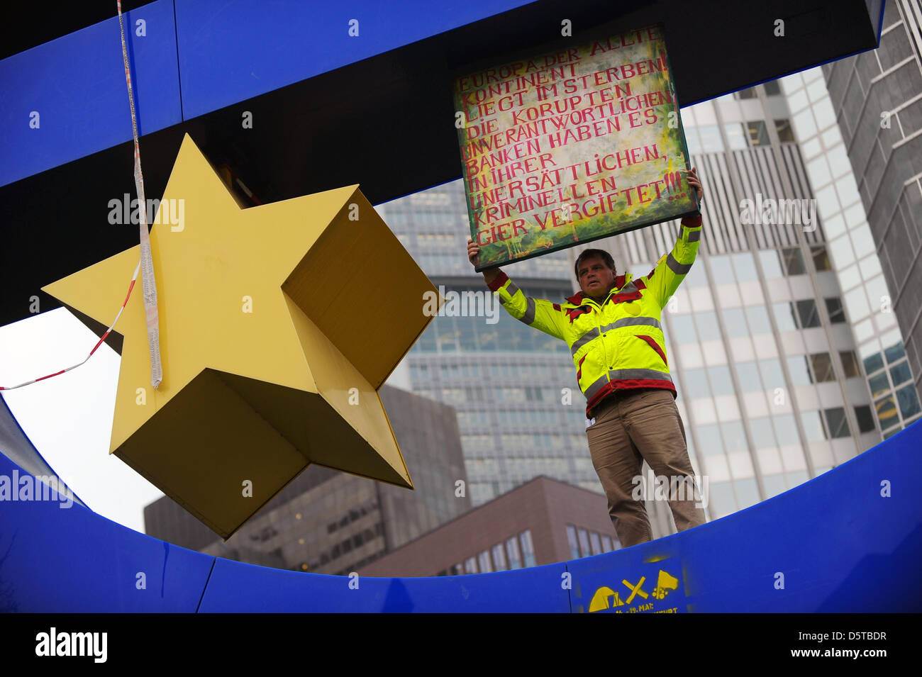 Estate agent Novak Petrovic stands on the euro symbol in front of the  European Central Bank headquarters in Frankfurt Main, Germany, 20 November  2012. By throwing fake bank notes, he wants to