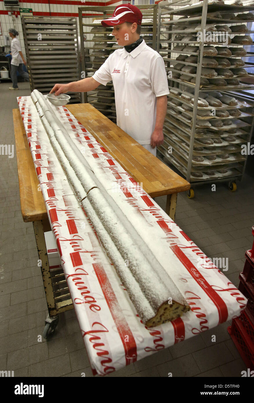 Sandra Jonas dusts the 3.6 m long giant Stollen with icing sugar at the city bakery Junge in Rostock, Germany, 23 November 2012. The fruit cake will be cut and handed out for free on 24 November 2012. It is baked according to a top secret family recipe from 1897. Photo: Bernd Wuestneck Stock Photo