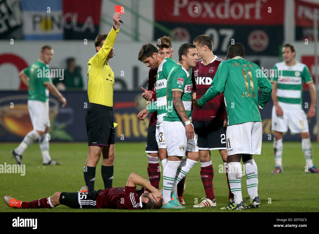 Referee Felix Brych (L) shows the red card to Fuerth's Sercan Sararer (C) next to Nuremberg's fouled Javier Pinola during the German Bundesliga match between SpVgg Greuther Fuerth and 1. FC Nuremerg at Trolli Arena in Fuerth, Germany, 24 November 2012. Photo: DANIEL KARMANN  (ATTENTION: EMBARGO CONDITIONS! The DFL permits the further utilisation of up to 15 pictures only (no sequnt Stock Photo
