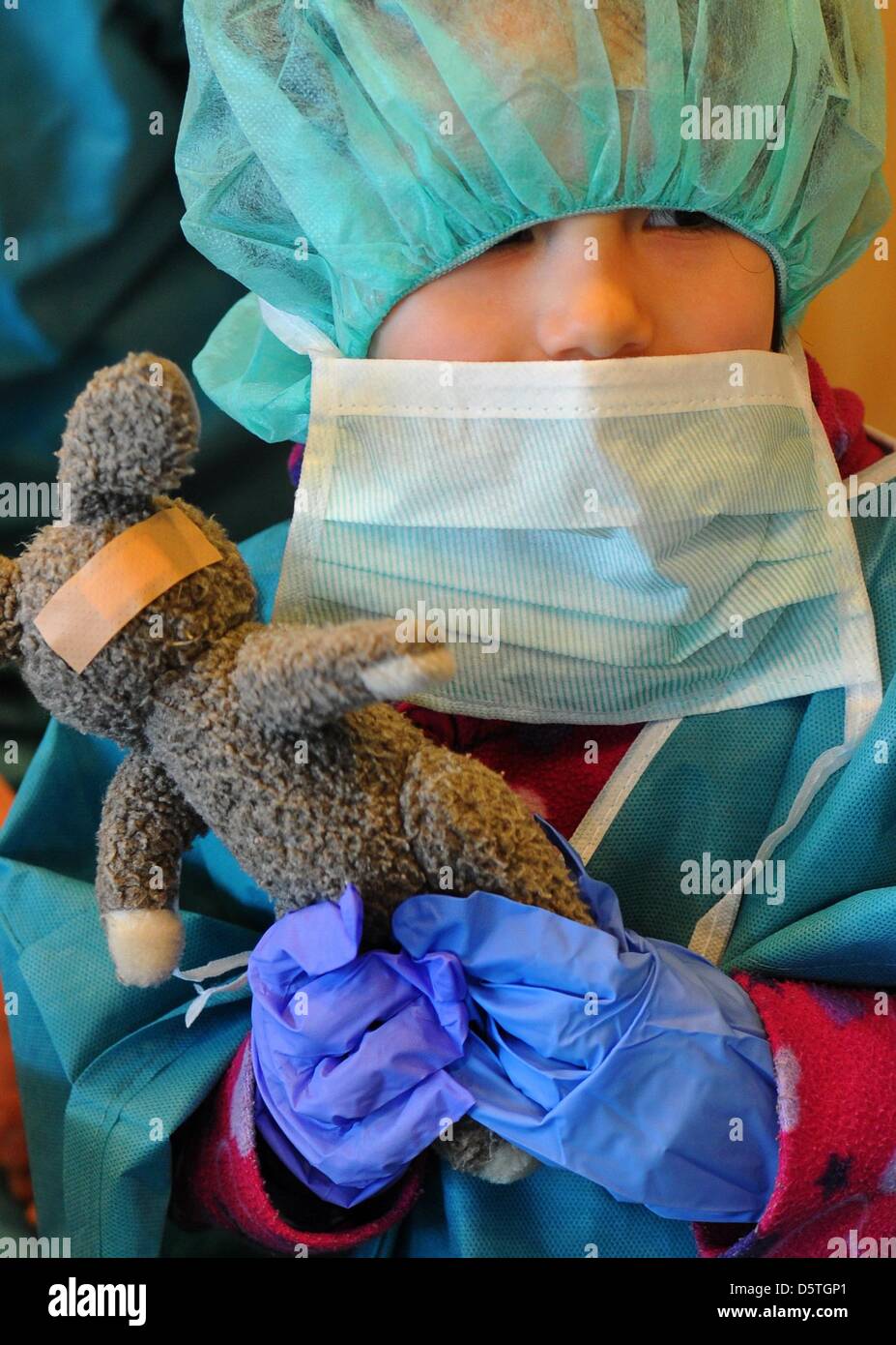 A child in scrubs stands with a bandaged stuffed rabbit in the ...
