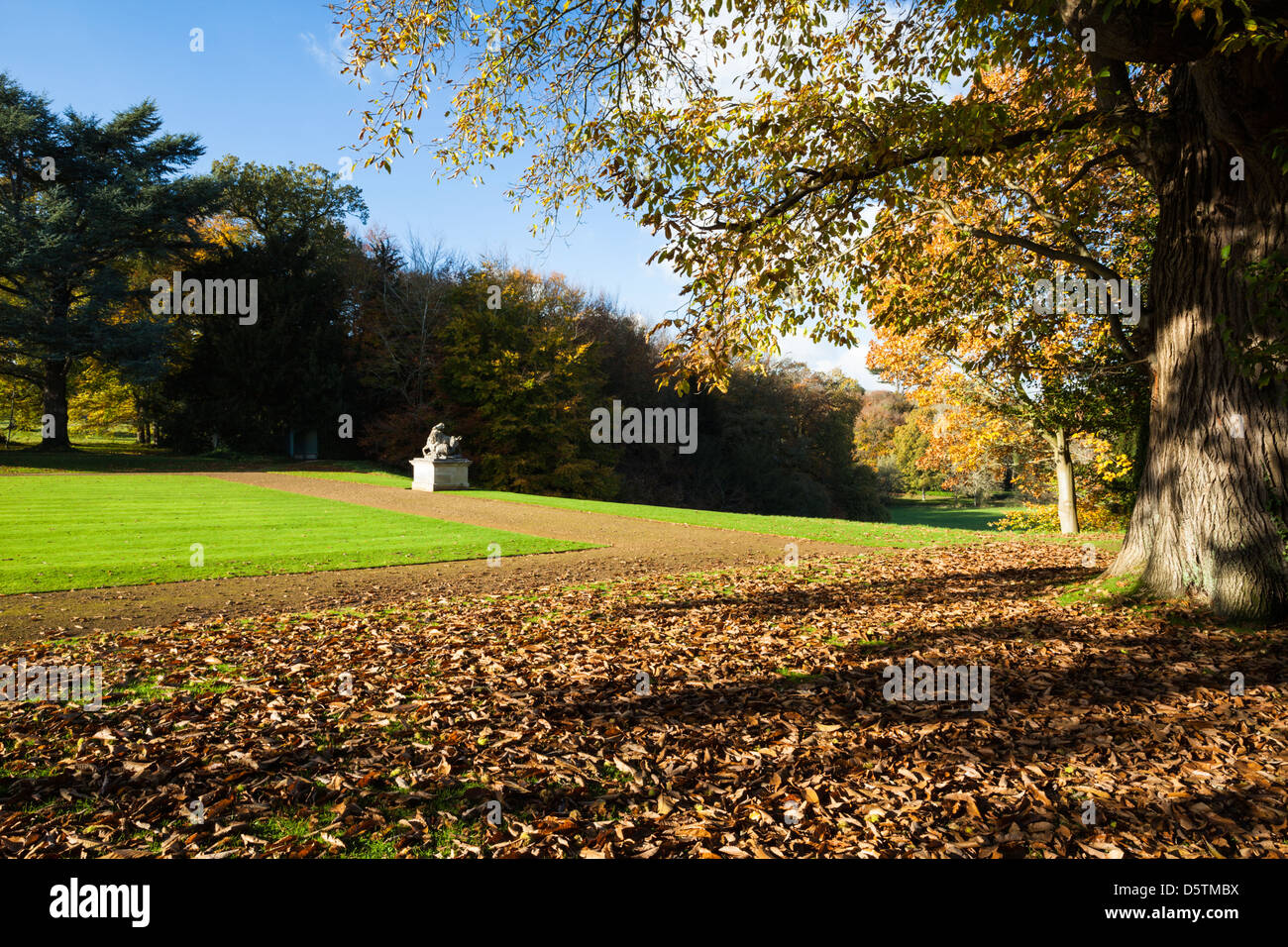 The landscaped gardens of Rousham House displaying their autumnal colours with a sculpture by Scheemaker on the edge of the path, Oxfordshire,England Stock Photo