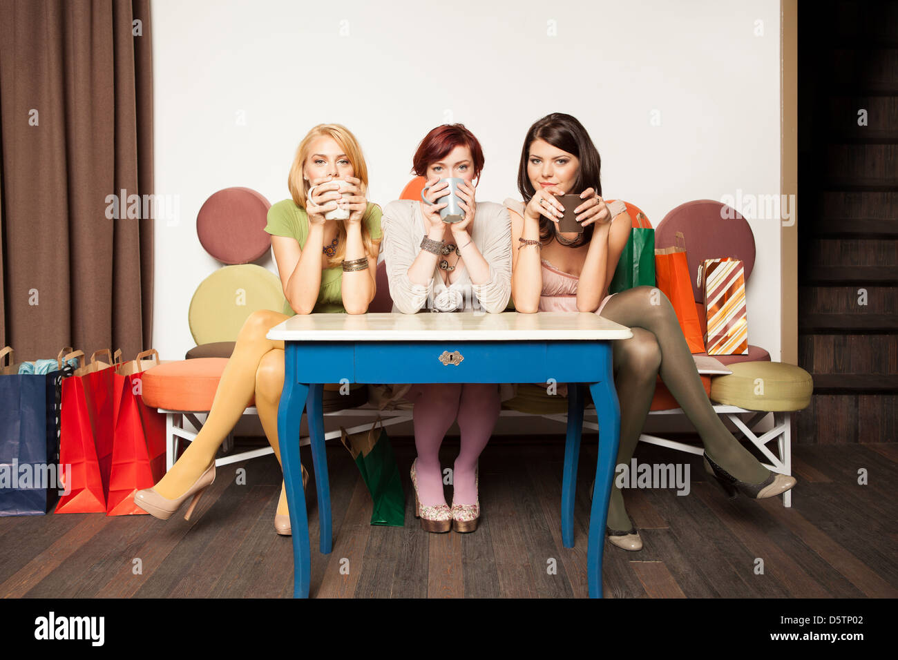 young girls sitting on a sofa drinking coffee Stock Photo - Alamy