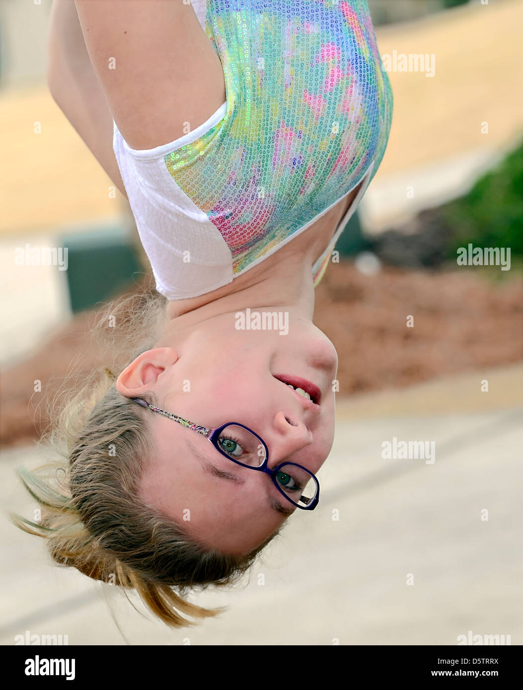 A cute girl having fun in a tree hanging upside down. Stock Photo