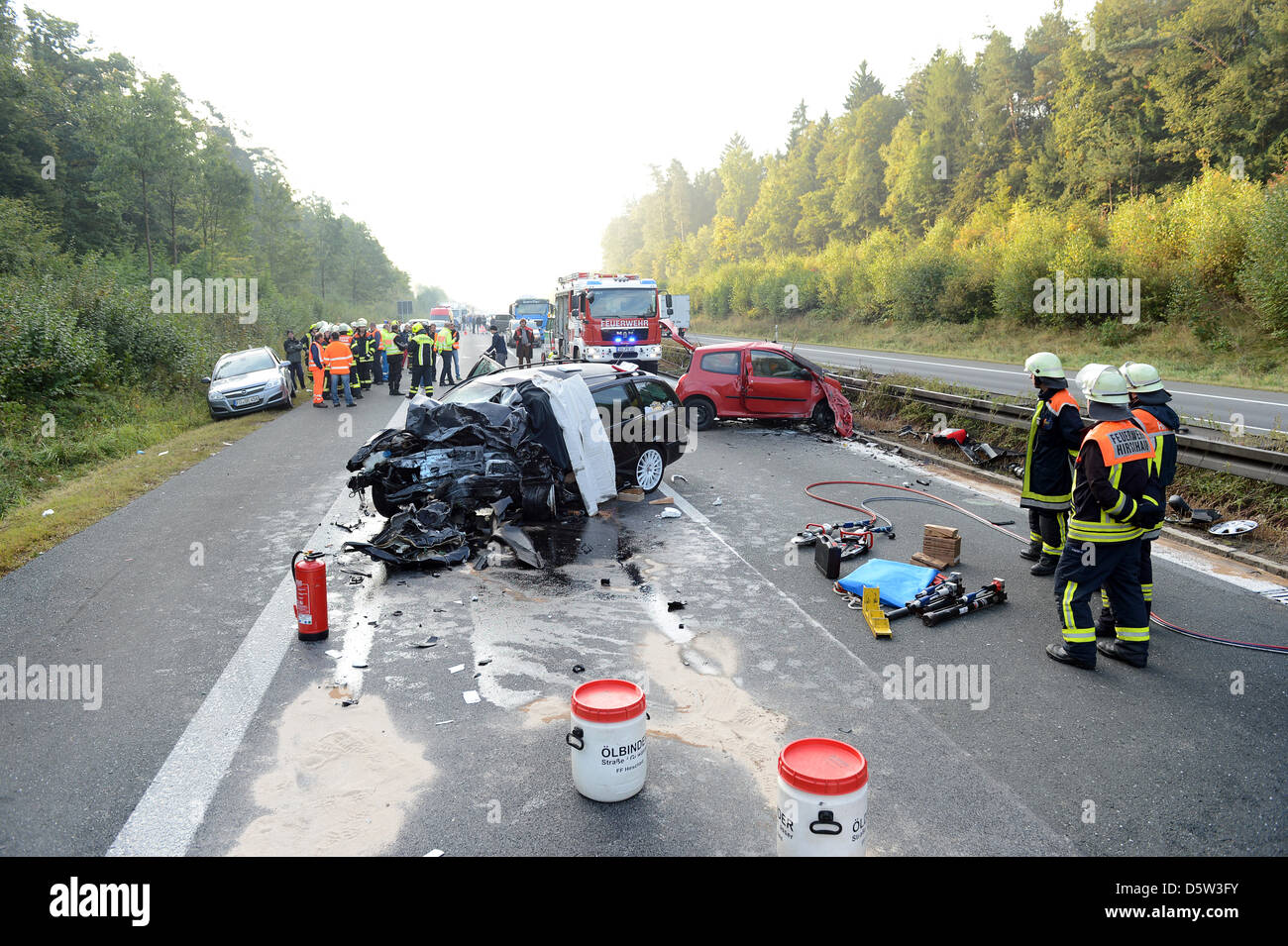 Emergency workers stand next to two severely damaged car after a ghost driver crash on Autobahn 73 near Hirschaid, Germany, 02 October 2012. A 31-year-old woman collided head-on with another car. The woman, a seven-year-old child and the driver coming in the opposite direction died at the scene. Photo: David Ebener Stock Photo