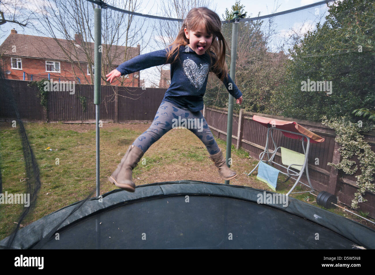 5 Year Old Girl Bouncing On A Garden Trampoline Stock Photo