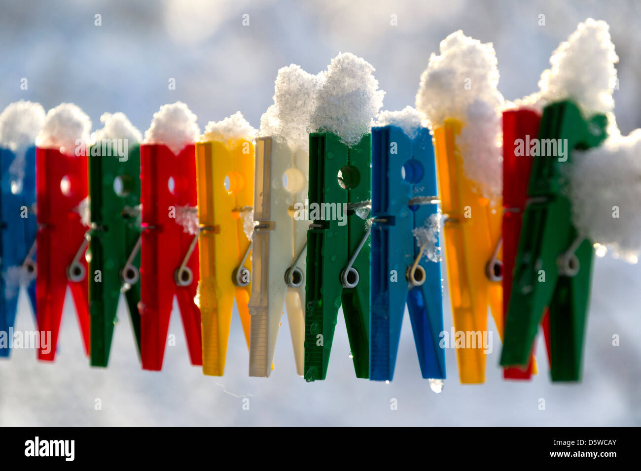 Washing line with a row of colorful pegs covered with snow queued in a row Stock Photo