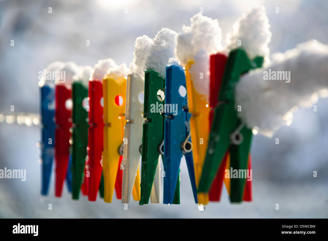 Washing line with a row of colorful pegs covered with snow queued in a row Stock Photo