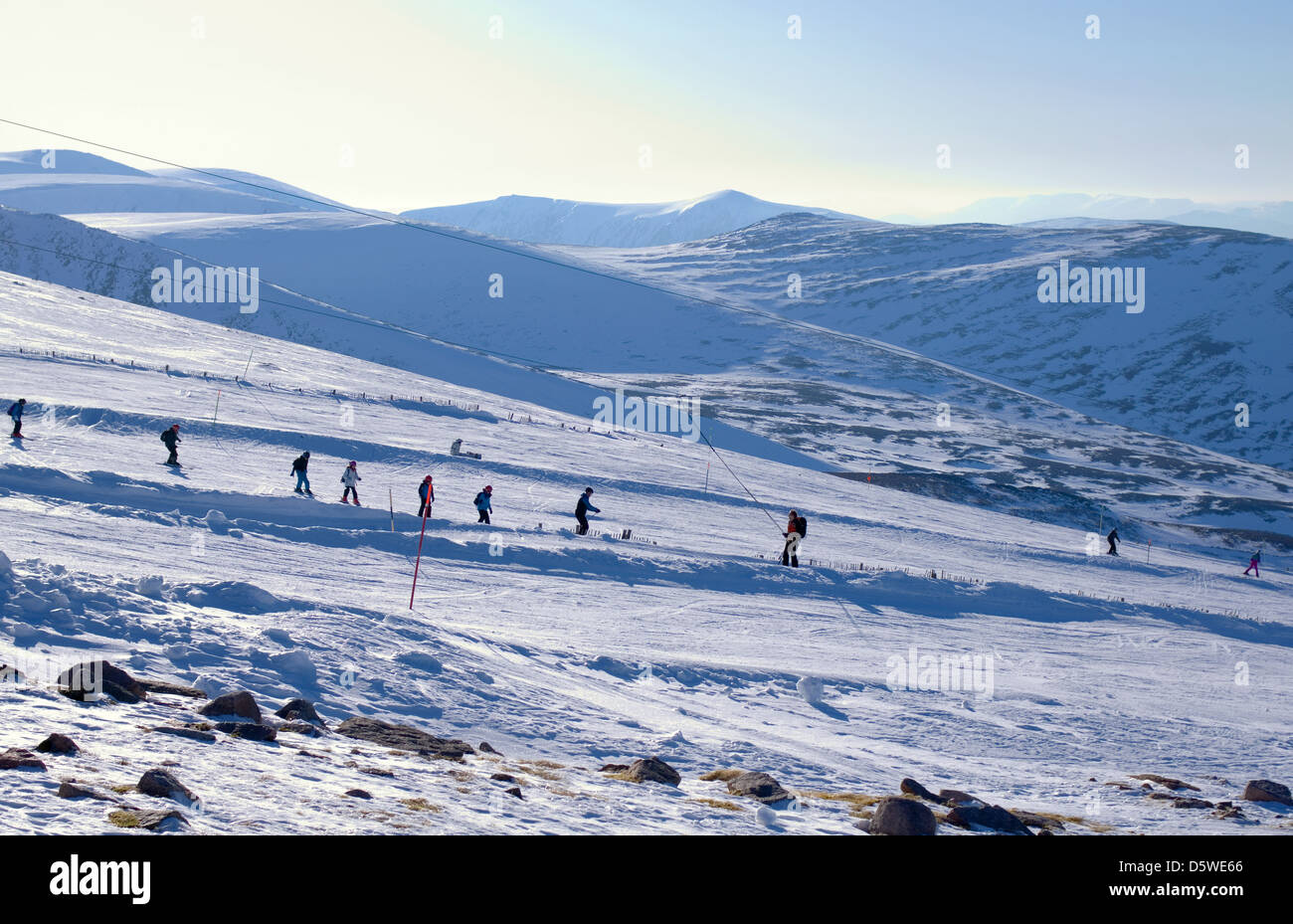 Skiers & snowboarders on tows and runs, seen from the Ptarmigan viewing terrace, Cairngorm Mountain Ski Centre Aviemore Scotland Stock Photo