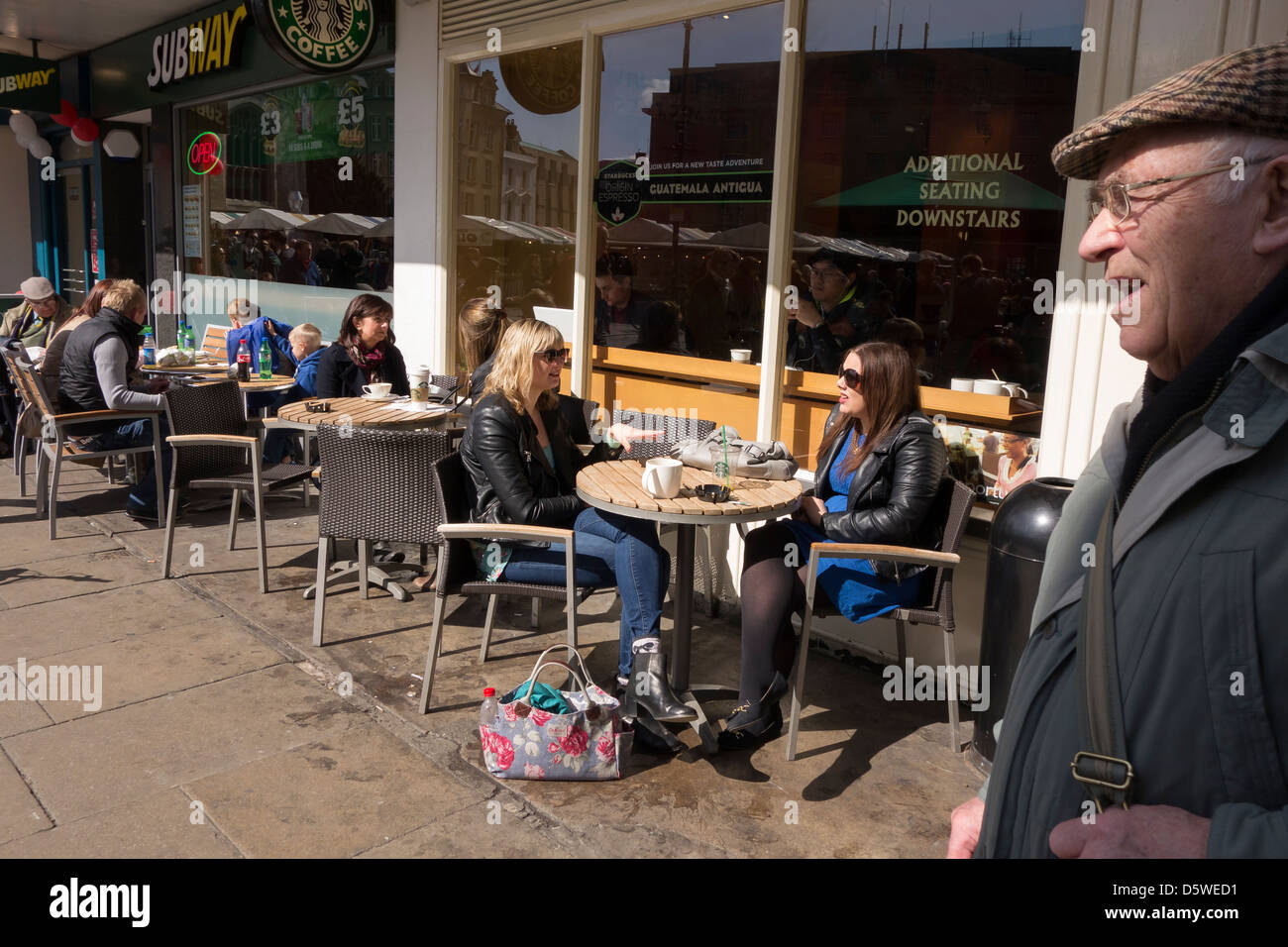 People enjoying the sun while snacking drinking resting alfresco outside of cafés Cambridge city England Stock Photo