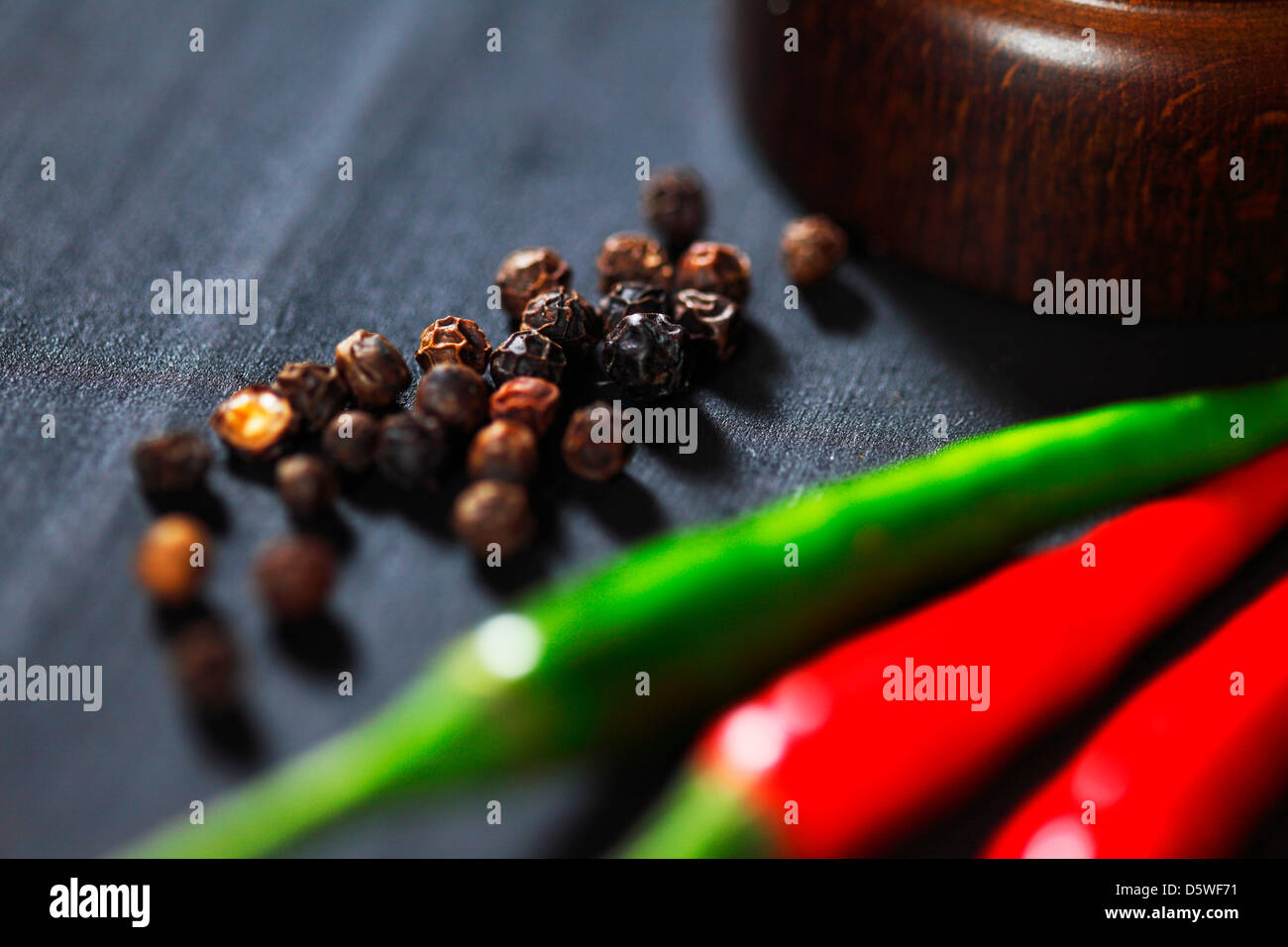 Wooden peppermill with pepper on black table Stock Photo Alamy