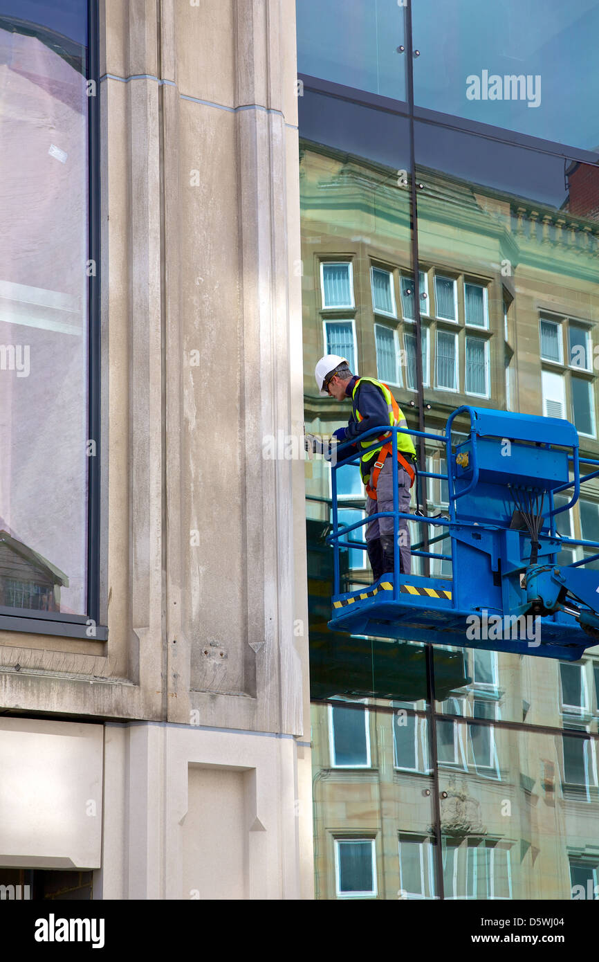 Workman on a cherry picker repairing the front of the building in Newcastle on Tyne, UK Stock Photo