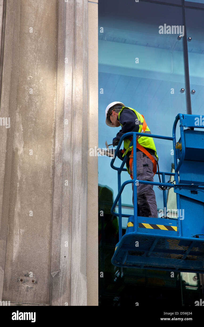 Workman on a cherry picker repairing the front of the building in Newcastle on Tyne, UK Stock Photo