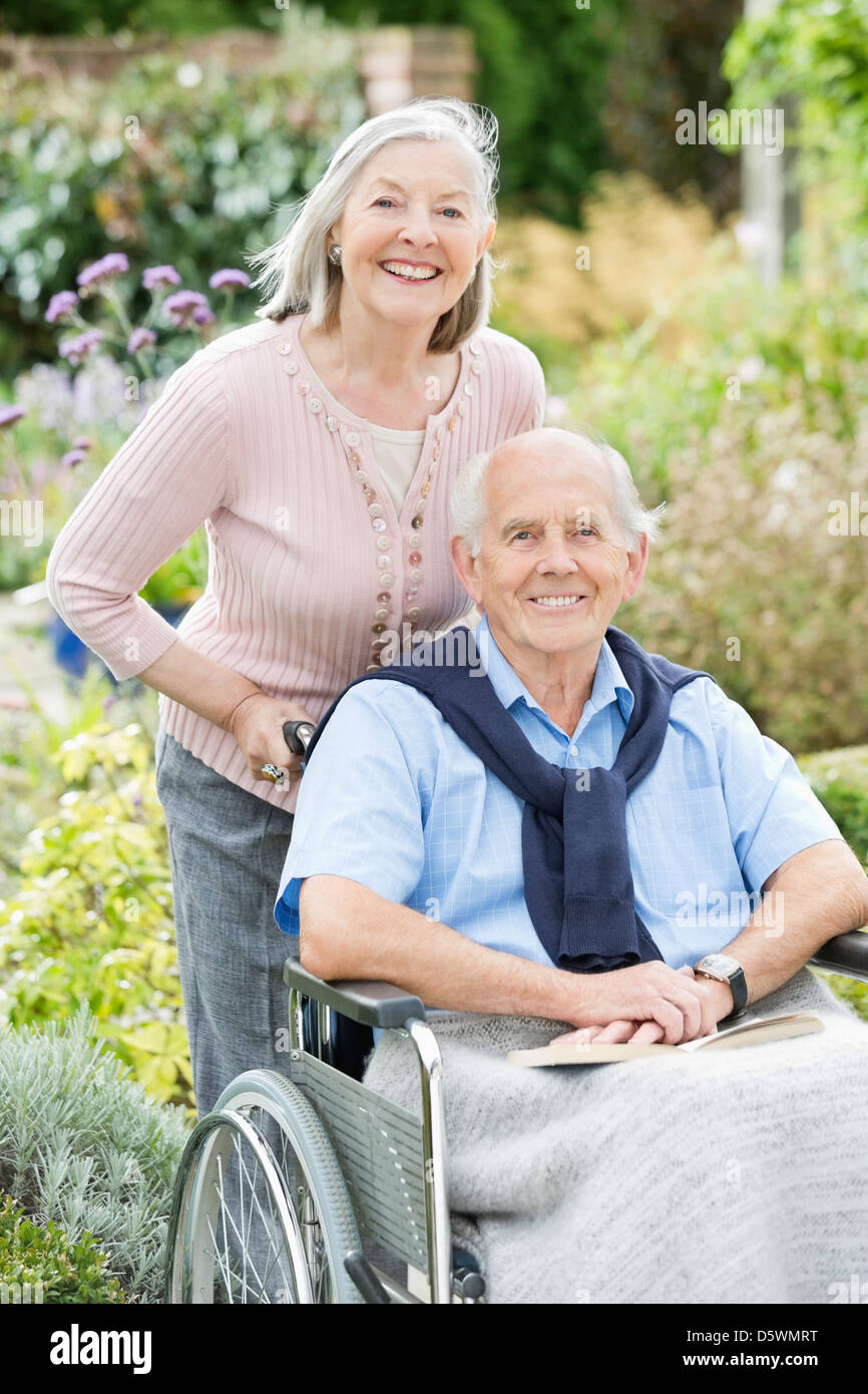 Older woman pushing husband's wheelchair outdoors Stock Photo