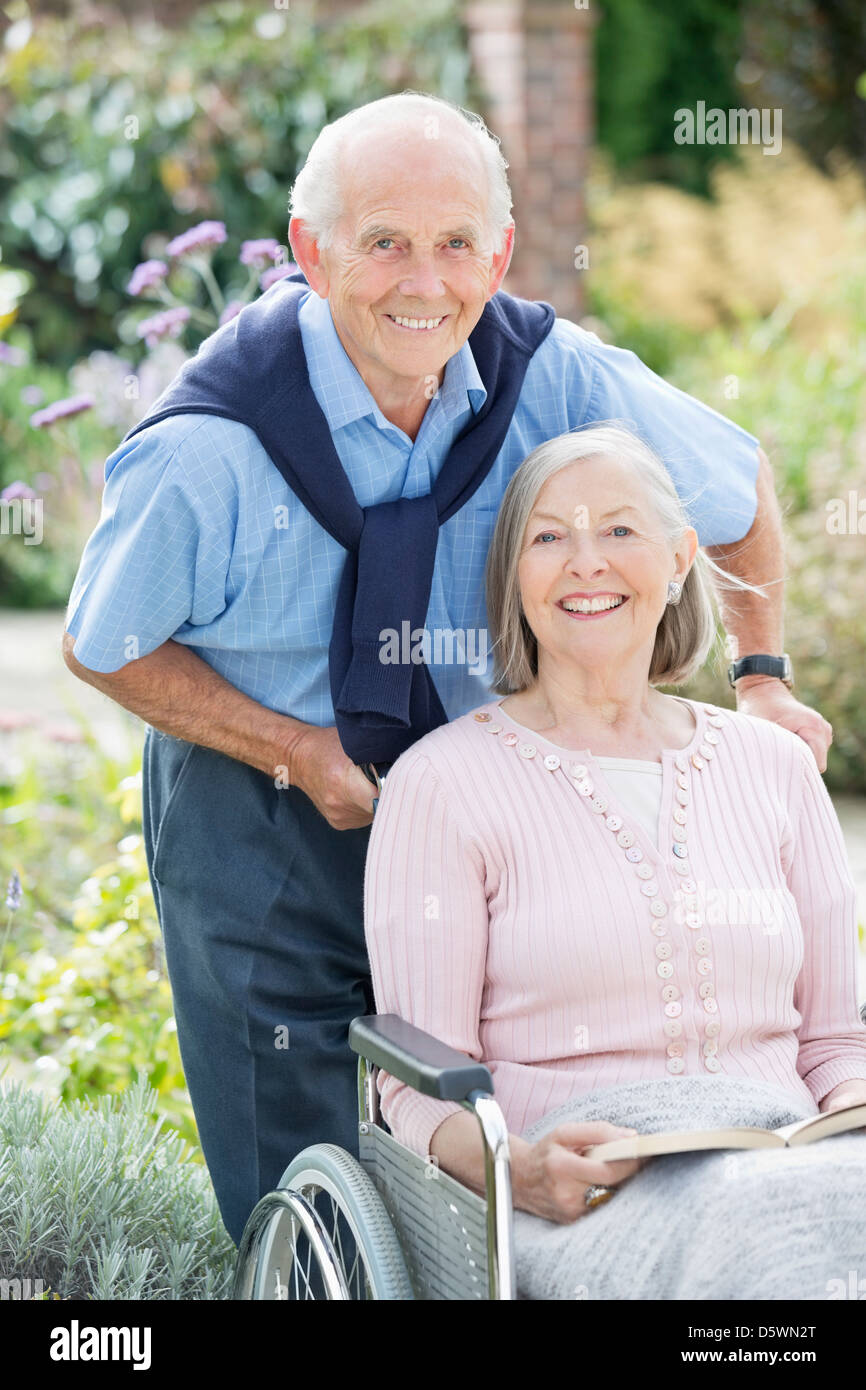 Older man pushing wife in wheelchair outdoors Stock Photo