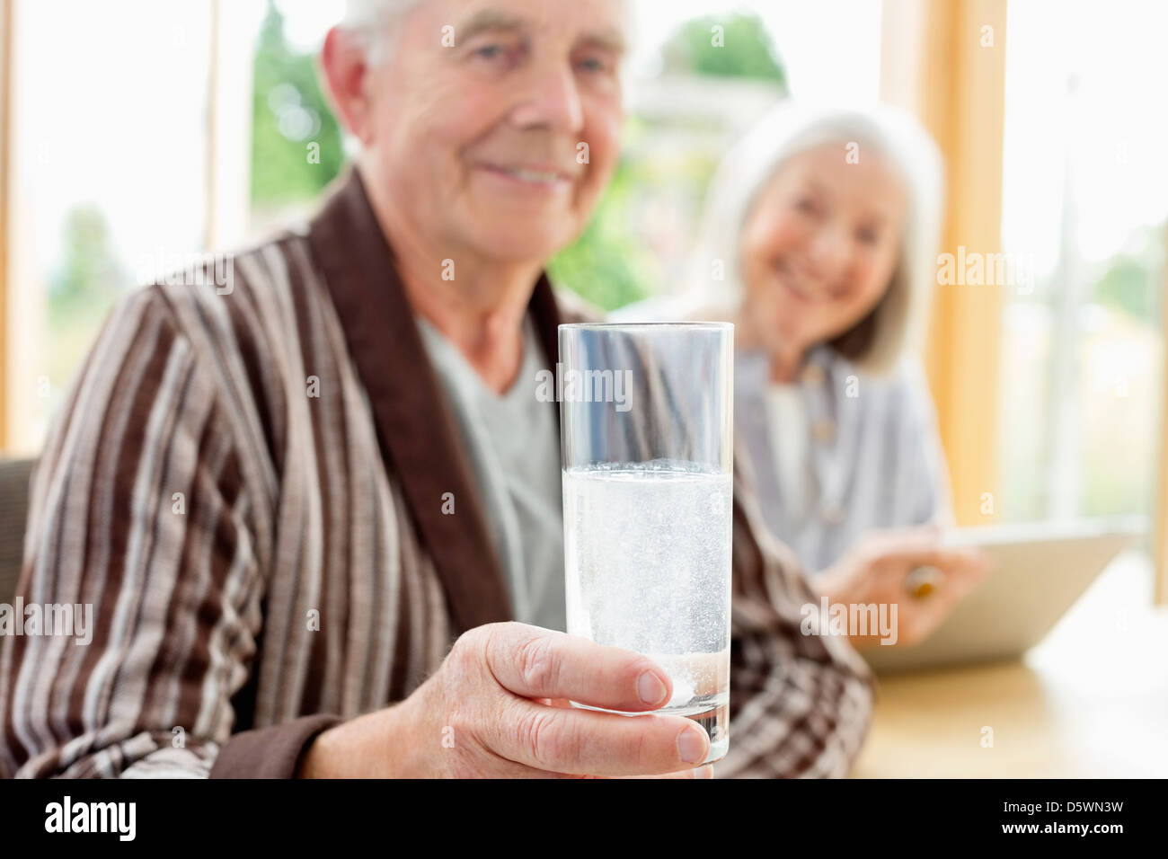 Older man taking medication in water Stock Photo