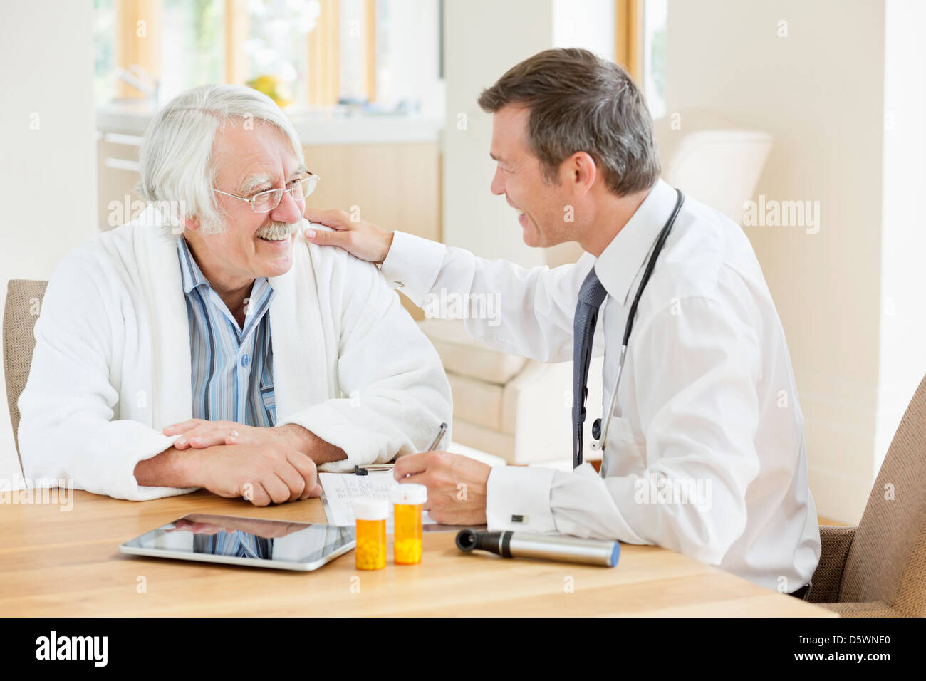 Doctor talking to older patient at house call Stock Photo